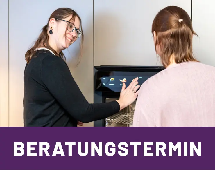 Mitarbeiterin im Kuechenhaus Gruber beraet Kundin zu Einbaubackofen