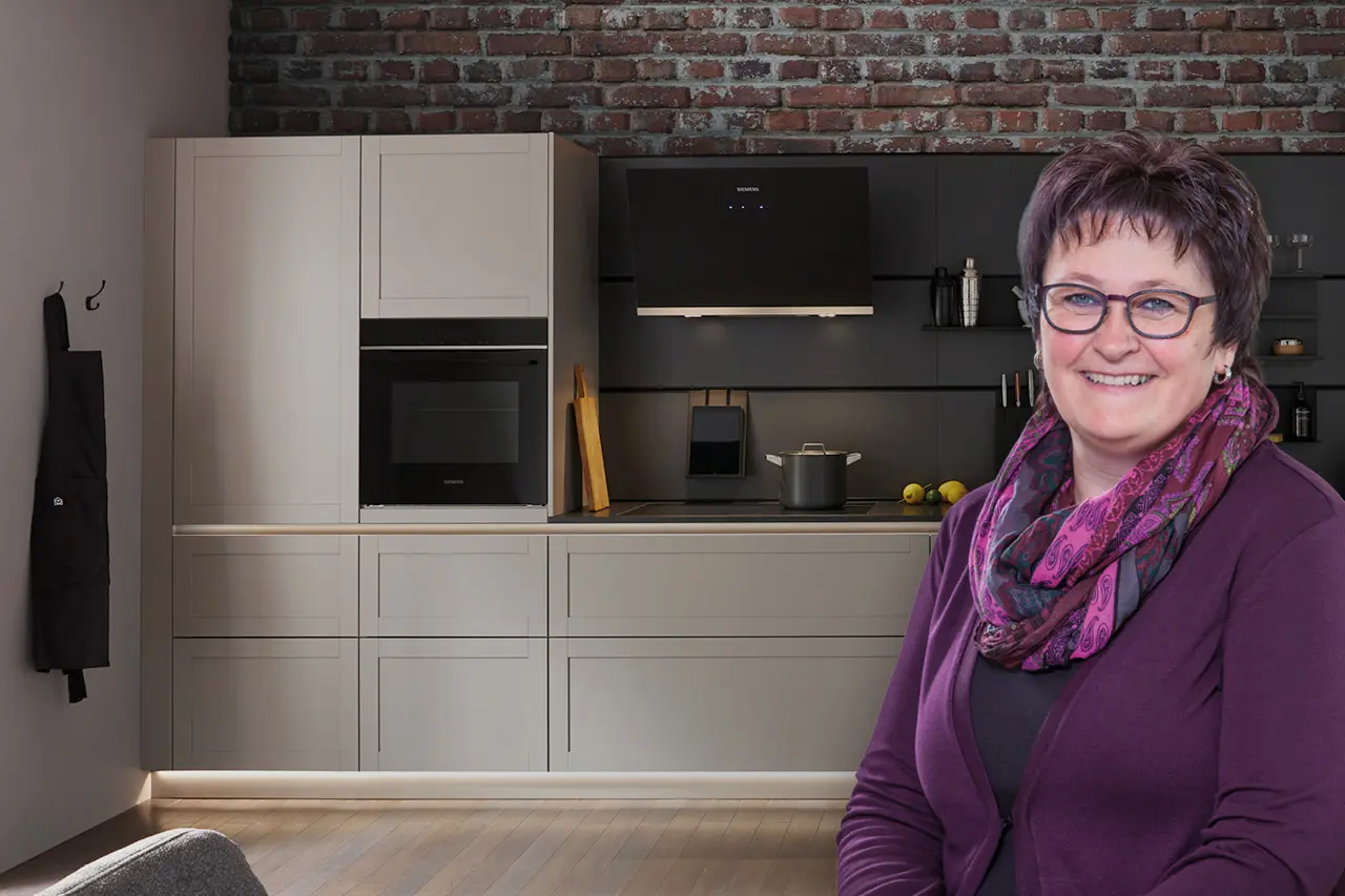 Beraterin im Küchenstudio vor moderner Einbauküche mit Backofen und Dunstabzug, individuelle Küchenplanung und kompetente Beratung für Ihre Traumküche.