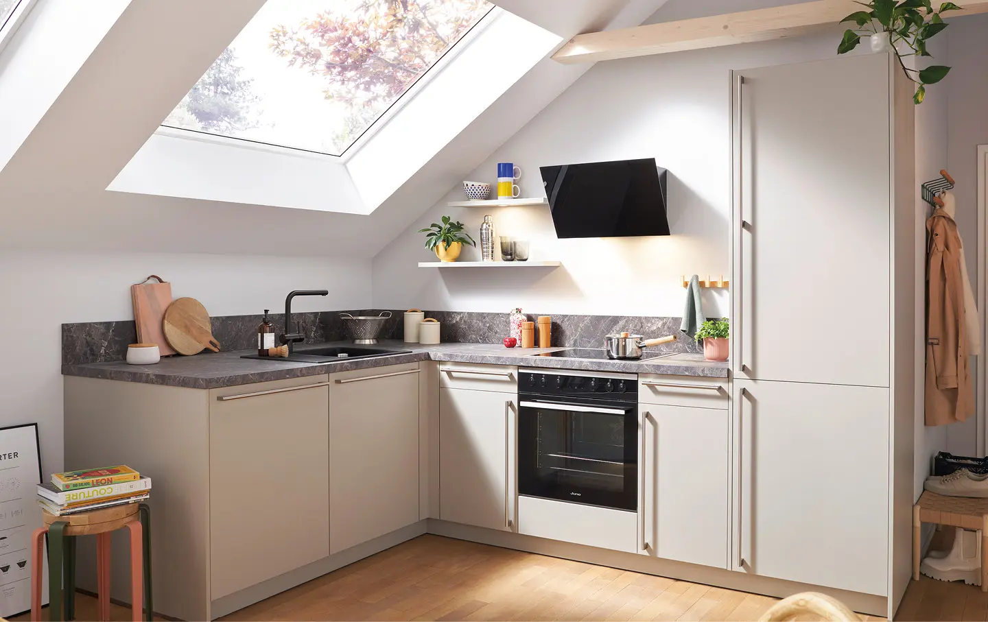 Helle Eckküche unterm Dachfenster mit dunkler Arbeitsplatte und Backofen.