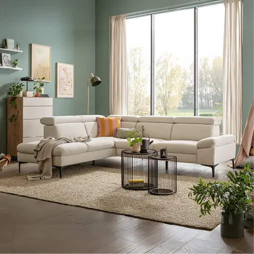 Helles Ecksofa im Wohnzimmer mit großem Fenster und Pflanzen