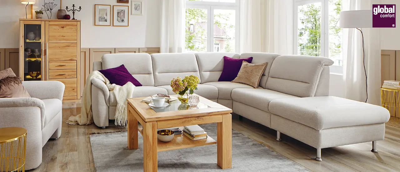 Global Comfort - Helle Sofaecke mit hölzernem Couchtisch und Vitrine