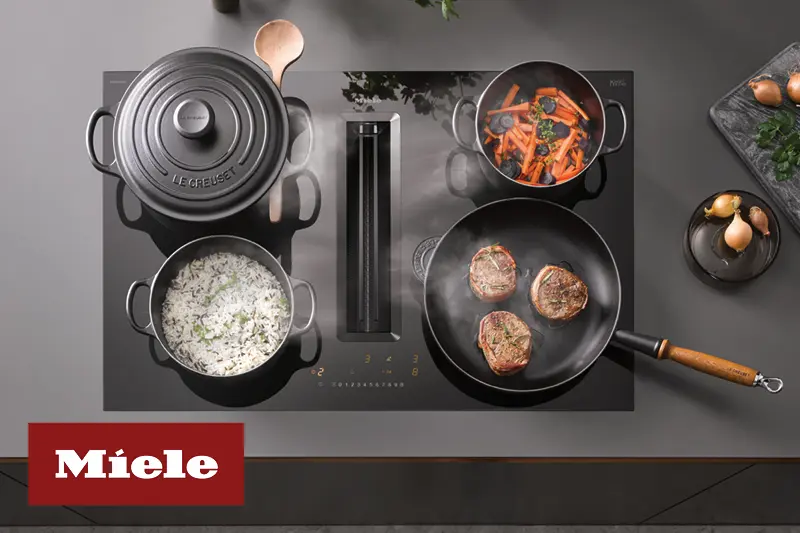 Schwarze Miele Herdplatte mit integriertem Muldenluefter und diverse Toepfe und Pfannen