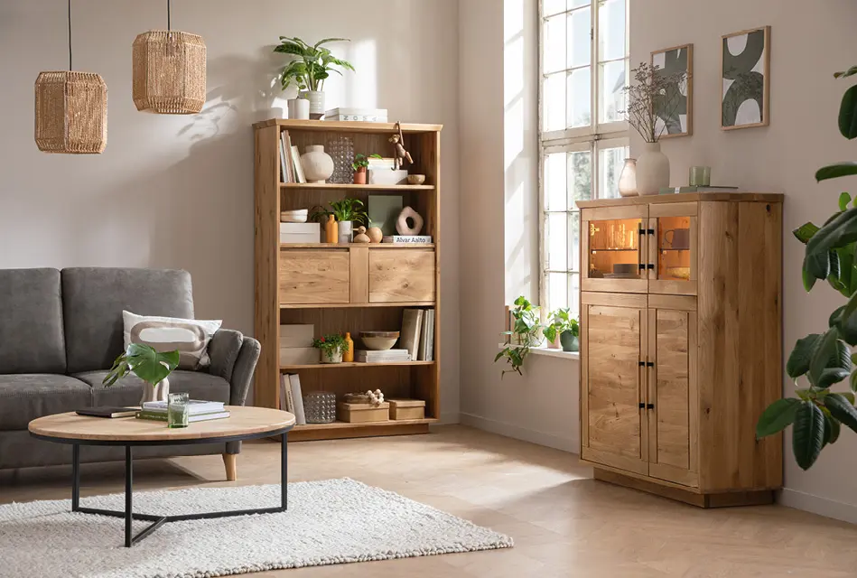 Modernes Wohnzimmer mit Sofa, Couchtisch und Massivholzregal. Hochwertige Wohnmöbel aus Holz, offene Regalfächer, warme Lichtakzente und Pflanzen schaffen eine natürliche und zeitlose Wohnatmosphäre.