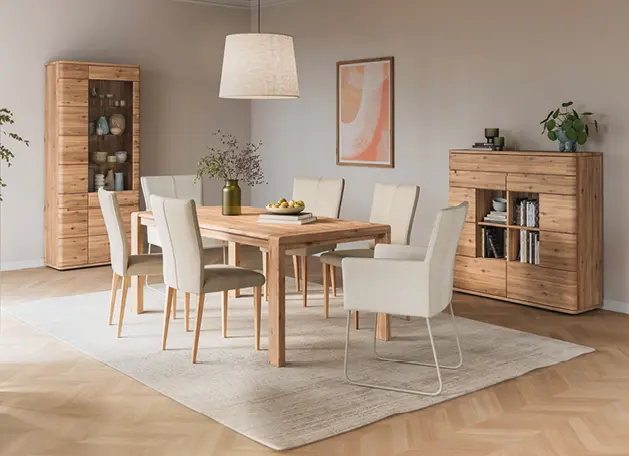 Esszimmer mit Holztisch, Polsterstühlen und Vitrine im Hintergrund