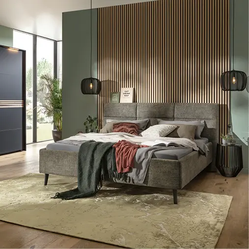 Doppelbett mit Polsterkopfteil vor Holzlamellenwand im Schlafzimmer