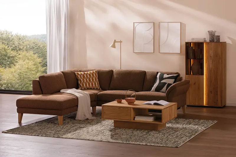 Wohnzimmer mit braunem Ecksofa, Holz-Couchtisch und beleuchtetem Schrank