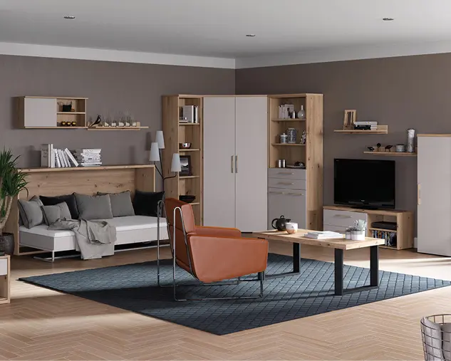 Modern eingerichtetes Wohnzimmer mit Wohnwand aus Holz, Schlafsofa, Sessel und Couchtisch in warmen Naturtönen. Offenes Wohnkonzept mit Stauraum, Regalflächen und harmonischer Beleuchtung für stilvolles Wohnen.