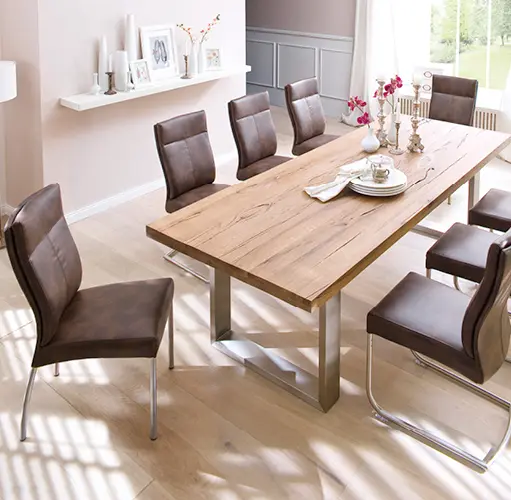 Esszimmer mit großem Esstisch aus Massivholz und sechs braunen Freischwinger-Stühlen auf hellem Parkett – moderne Essgruppe, natürliche Materialien, gemütliches Ambiente für stilvolles Wohnen.