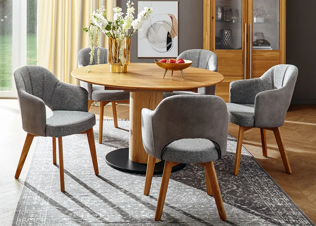 Vier graue Esszimmerstühle an rundem hölzernen Esstisch im Esszimmer