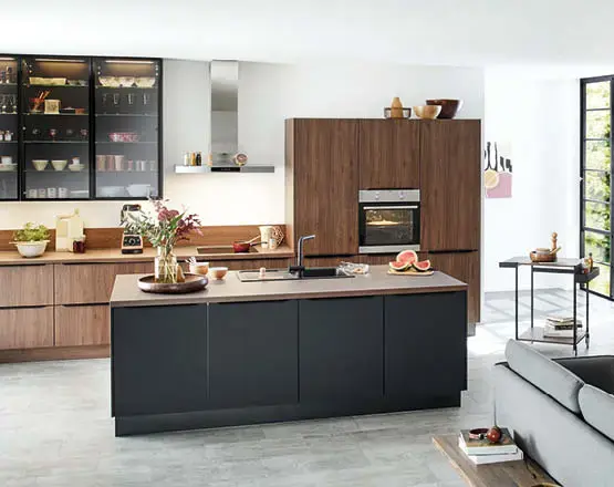 Küche mit dunkler Kücheninsel, Holzfronten, Vitrinenschrank links und Backofenhochschrank im offenen Wohnraum.