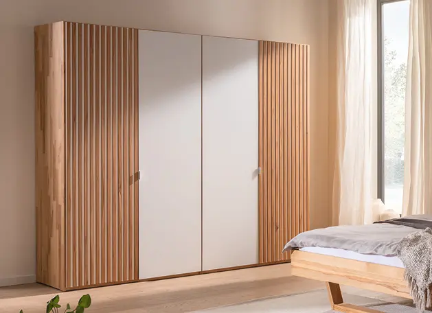 Kleiderschrank mit Holzlamellen und weißen Schiebetüren im Schlafzimmer