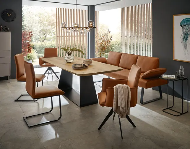 Modernes Esszimmer mit großem Esstisch, bequemen Polsterstühlen in Lederoptik und Designleuchte. Hochwertige Einrichtung für Essbereich, Wohnen und stilvolle Wohnkonzepte mit viel Tageslicht.