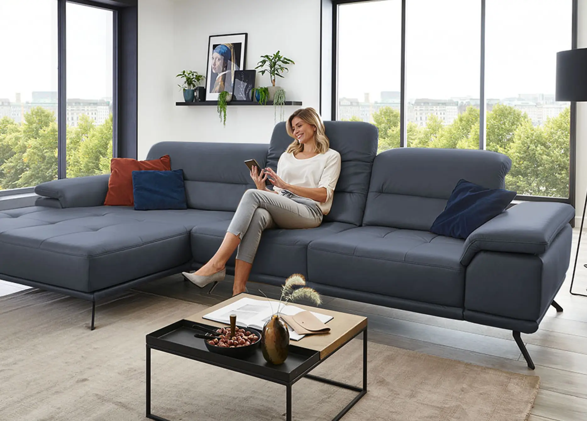 Blonde Frau sitzt mit Tablet auf Sofa