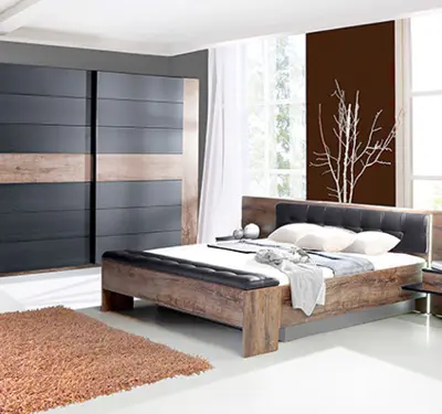 Schlafzimmer mit Holzbett und gepolstertem Kopfteil, links großer Schiebetürenschrank in Schwarz und Holzoptik, rechts hohe Fensterfront und brauner Teppich.