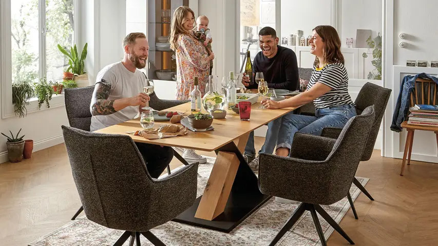 Menschen sitzen gemeinsam am Esstisch mit gepolsterten Stühlen im Esszimmer