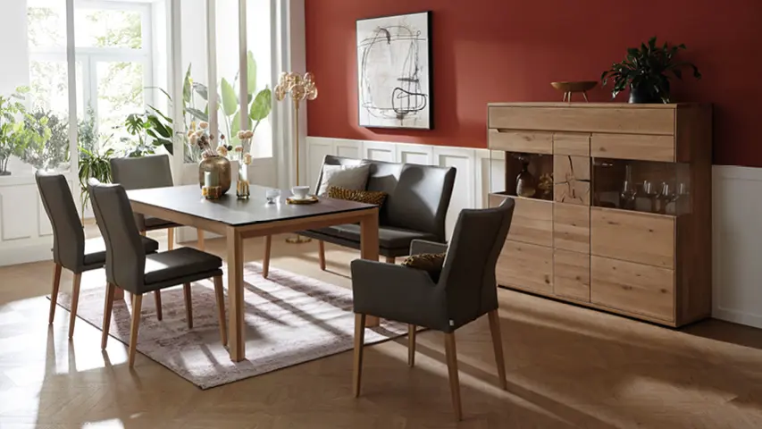 Esstisch mit gepolsterten Stühlen in wohnlichem Esszimmer mit Sideboard