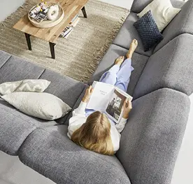 Frau relaxend auf hellgrauem Sofa in Wohnzimmer