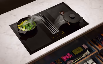 Kochfeld von Miele, das die Funktion zeigt, eine eingebaute Dunstabzugshaube zu haben, die beim Kochen den entstehenden Dampf direkt abzieht.&nbsp;