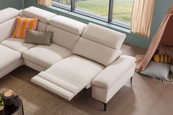 Beiges Ecksofa mit ausgeklappter Fußlehne und Kopfstütze.