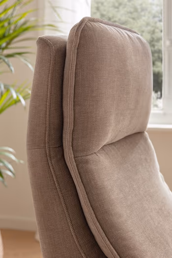 Seitliche Aufnahme der bequem gepolsterten Kopflehne eines beigen Relaxsessels.