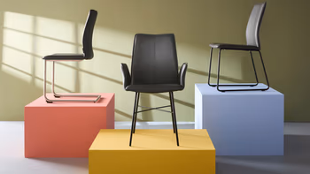 Modernes Zimmer mit drei Freischwinger Stühlen die auf bunten Blöcken dekorativ platziert sind. 