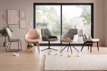 Fünf Stühle mit und ohne Armlehne in rosa und grauem Stoff bezogen mit Füßen aus Holz oder in schwarz in einer Reihe.