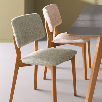 Zwei Esszimmerstühle im Skandi Look nebeneinander mit naturfarbenem und grünem Bezug.