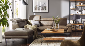 Stylisches dunkelbraunes Ledersofa mit Liegeflaeche in gemuetlich eingerichtetem Wohnzimmer.