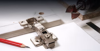 Bohrmaschine und Handwerkerbleistift auf Schranktüre mit Scharnier.