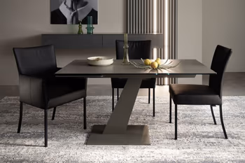 Kleiner Design Esstisch mit schwarzer Tischplatte und grauem schrägem Tischgestell, um den Tisch stehen drei schwarze Stühle.