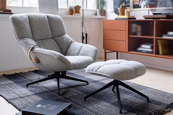 Grauer Sessel mit passendem Hocker. 