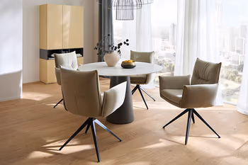 Heller Essbereich mit rundem Esstisch, vier Armlehnstühlen und gelbem Highboard.