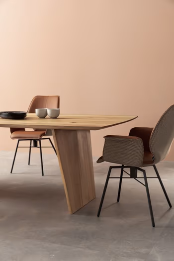 Massivholz Esstisch mit Tischplatte in organischer Form, an dem zwei moderne Schalenstühle stehen.