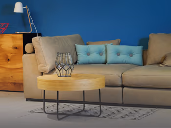 Ein Beistelltisch aus Holz vor einem Sofa. Im Hintergrund eine blaue Wand.