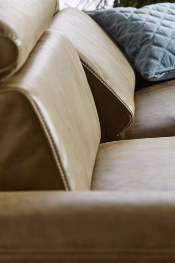 Sitzfläche eines grünen Ledersofas, bei dem eine Rückenlehne etwas nach vorne geklappt ist.