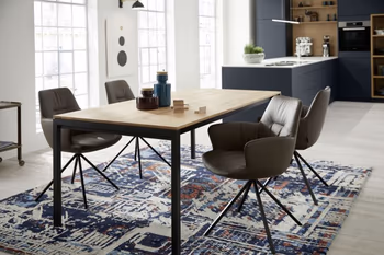 Modernes Esszimmer mit einem Holzesstisch und bequem gepolsterten Schalenstühlen mit grauem Lederbezug und schwarzem Fußgestell.