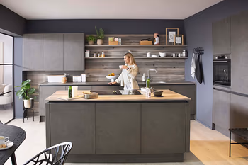 Frau trinkt Kaffee in einer modernen Küche im Beton-Look-