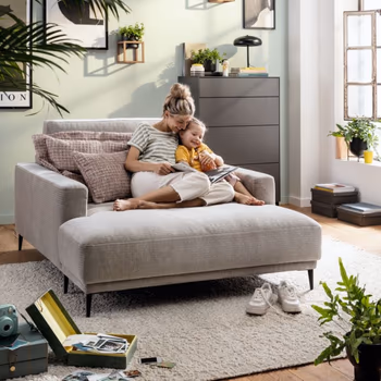 Großer Loungesessel in grau, auf dem eine Frau und ein Kind liegen und lesen.