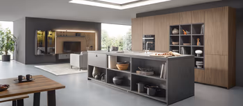 Dunkelgraue Contur Kueche mit Kuecheninsel und Holzfronten in grossem offenem Wohnbereich.