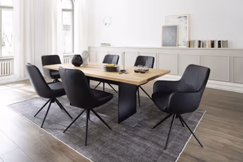 Modernes Esszimmer, in dem ein Designer Esstisch aus Massivholz mit Metallfuß in schwarz steht, um den Tisch stehen moderne schwarze Schalenstühle mit und ohne Armlehne.