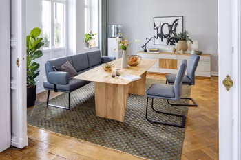 Modernes Esszimmer mit einer Sitzbank mit Armlehne und dazu passenden Freischwingern in blauem Leder mit schwarzem Metallgestell.