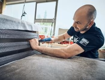 Mann in einer Produktionsstätte von global Wohnen der ein Möbelstück montiert.