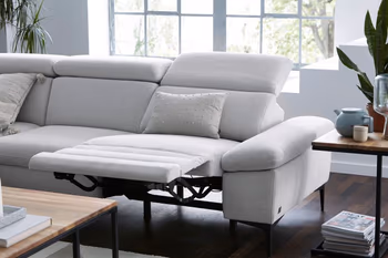 Hellgraues Sofa mit hochgeklappter Fußstütze und nach hinten geklappter Rückenlehne.