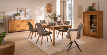 Moderne graue Stühle mit holzgestell und zwei graue Armlehnstühle mit schwarzem Metallgestell um einen Massivholzesstisch.