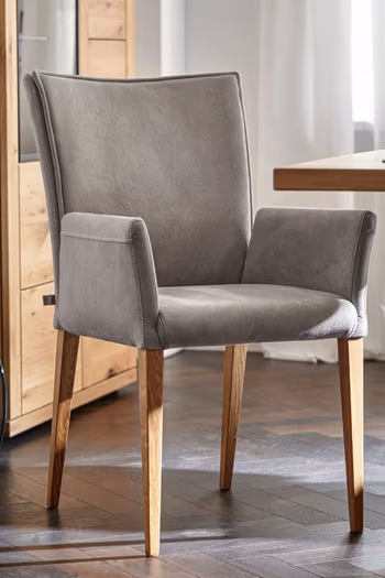 Grauer Esszimmerstuhl mit Armlehnen und Holzgestell in einem hellen Raum.