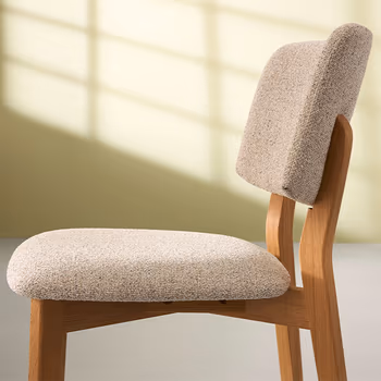 Esszimmerstuhl im Skandi Look mit Massivholz Gestell und beigem Stoff an Rückenlehne und Sitzfläche.