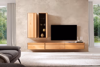 Moderne Wohnwand aus Massivholz bestehend aus einem hängenden Lowboard und einem hängenden Wandregal neben einem Wandschrank.