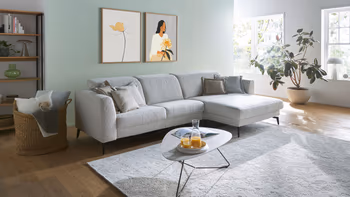 Hellgraues Ecksofa mit filigranen schwarzen Füßen und einem eleganten dreieckigen Beistelltisch.