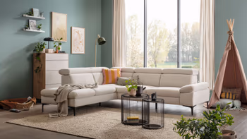 Modernes beiges Ecksofa in einem gemütlichen Raum mit Kinderspielzeug.