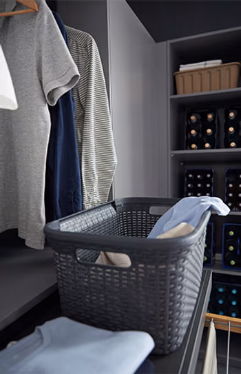 Wäscheschrank in einem grauen Hauswirtschaftsraum mit ausziehbarer Ablage.